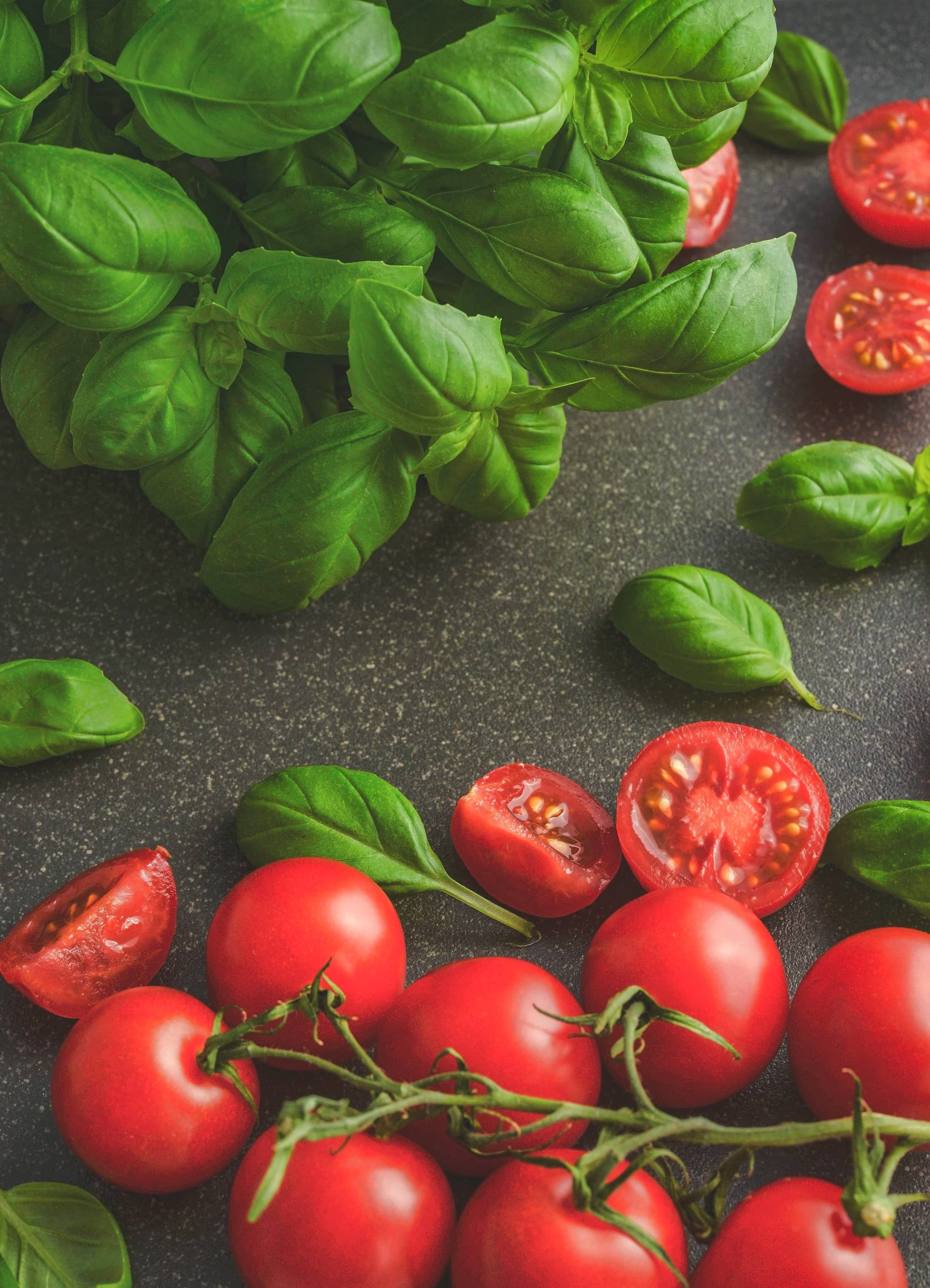 Frische Tomaten und Basilikum auf dunklem Stein