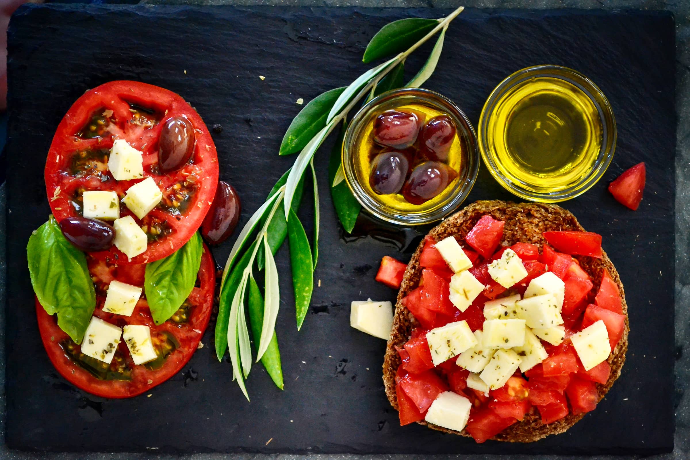 Tomaten, Käse, Oliven und Olivenöl auf einer Schieferplatte