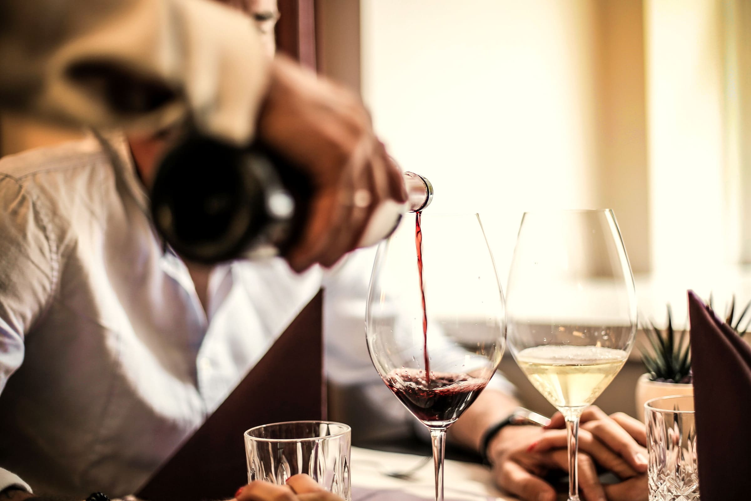 Rotwein wird am Tisch eingeschenkt